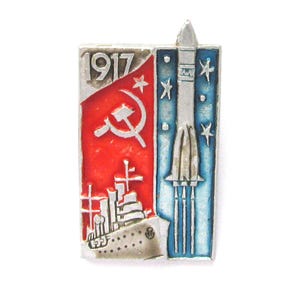 Puede incluir: Pin vintage plateado con una bandera roja, una hoz y un martillo, y el año "1917". El pin también presenta un barco y un cohete sobre un fondo azul estrellado. Un artículo de colección.