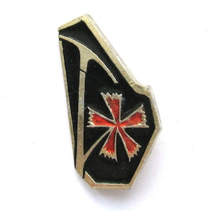 Puede incluir: Un pin vintage con fondo negro y diseño de cruz roja. El pin tiene un borde plateado y una forma geométrica única. La cruz está detallada con esmalte rojo, agregando un toque de color al diseño.