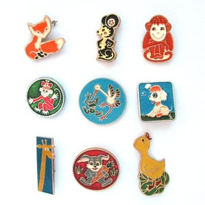 Puede incluir: Nueve pines de esmalte con diferentes diseños de animales. Los pines son de forma circular, cuadrada y rectangular. Los animales incluyen un zorro, un mono, una jirafa, un pato, un conejo, una rana, una cigüeña, un perro y un ratón.