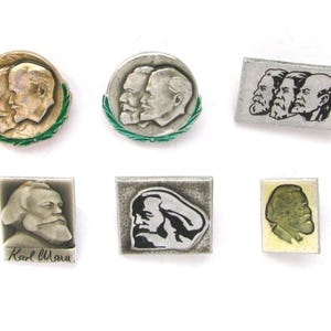 Puede incluir: Colección de broches metálicos vintage con retratos de figuras históricas. Los broches, de formas variadas (redondos, rectangulares), presentan retratos en relieve detallados en plata, oro y blanco y negro.