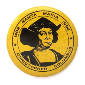 May include: A round, yellow button featuring a black and white portrait of Christopher Columbus. The button has the text "SANTA MARIA 1492 1992 CHRISTOPHER COLUMBUS" in a circular pattern around the image.