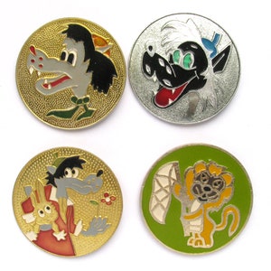 以下が含まれることがあります： 漫画のキャラクターが描かれた丸い金属製のピンが4つあります。最初のピンは金色で、緑色のスカーフをした灰色のオオカミが描かれています。2番目のピンは銀色で、青い帽子をかぶった黒いオオカミが描かれています。3番目のピンは金色で、ウサギを抱いた灰色のオオカミが描かれています。4番目のピンは緑色で、白い布を持った黄色のライオンが描かれています。