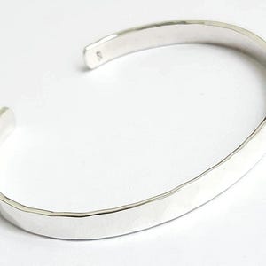 May include: A silver hammered bangle bracelet with a smooth, polished finish.
