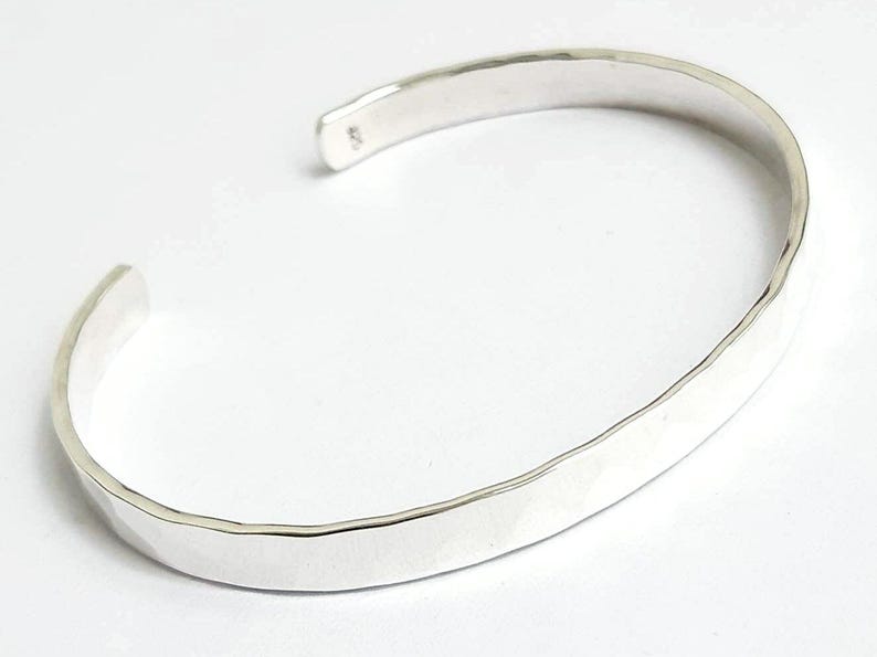 May include: A silver hammered bangle bracelet with a smooth, polished finish.