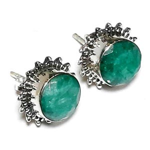 Puede incluir: Un par de pendientes de bot&oacute;n con piedras preciosas redondas, facetadas, de color verde esmeralda. Las piedras preciosas est&aacute;n engastadas en un metal plateado con un borde decorativo y puntiagudo. Sobre un fondo blanco.