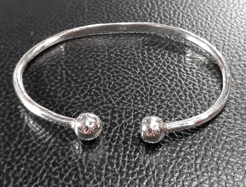 Op de afbeelding: Een zilveren armband met twee ronde, getextureerde uiteinden.