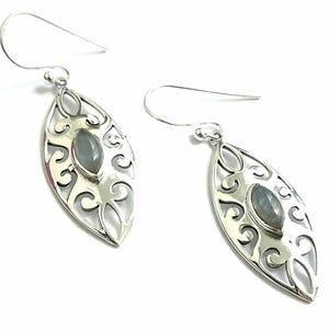 May include: Silver dangle earrings with a delicate filigree design and a gray gemstone in the center.
