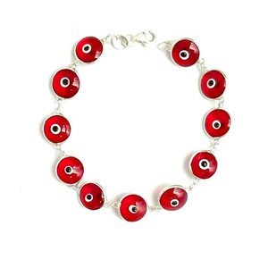 May include: A silver bracelet with red evil eye charms. The bracelet has a lobster clasp closure.