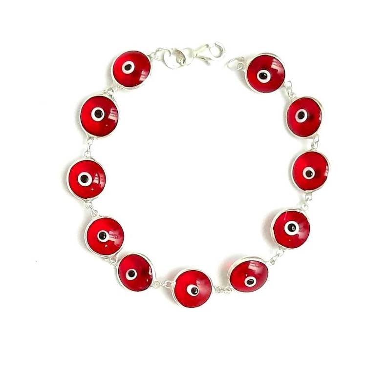 May include: A silver bracelet with red evil eye charms. The bracelet has a lobster clasp closure.