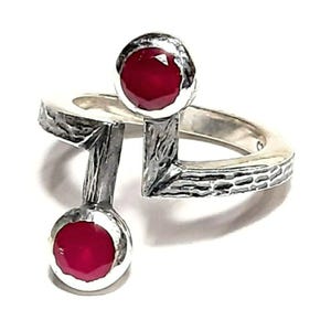 Op de afbeelding: Een zilveren ring met twee rode edelstenen. De ring heeft een getextureerde band en een uniek ontwerp.