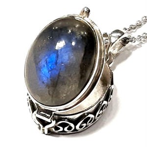 Peut inclure: Un collier avec un pendentif en argent orn&eacute; d'une grande pierre de labradorite ovale. Le pendentif est ouvrable et pr&eacute;sente un motif argent&eacute; d&eacute;taill&eacute; sur le bord.