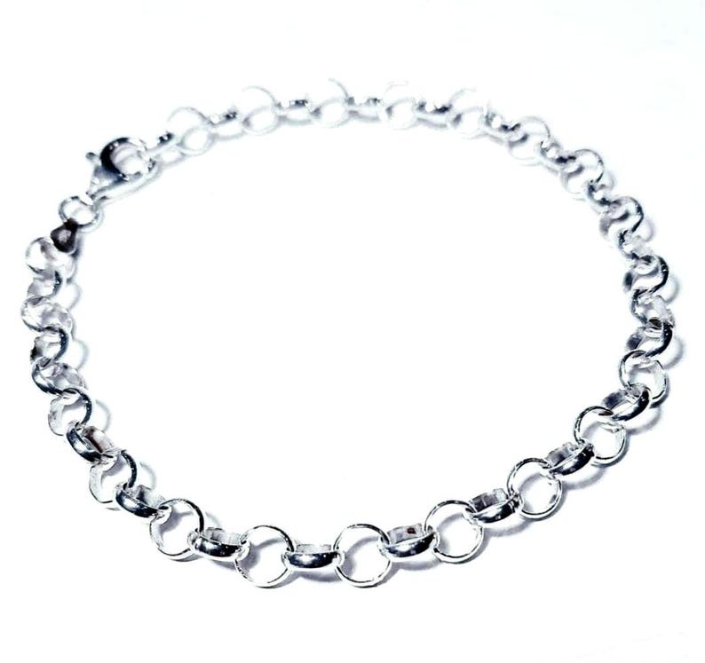 Puede incluir: Un brazalete de cadena de plata con cierre de mosquet&oacute;n. La cadena est&aacute; hecha de peque&ntilde;os eslabones redondos.