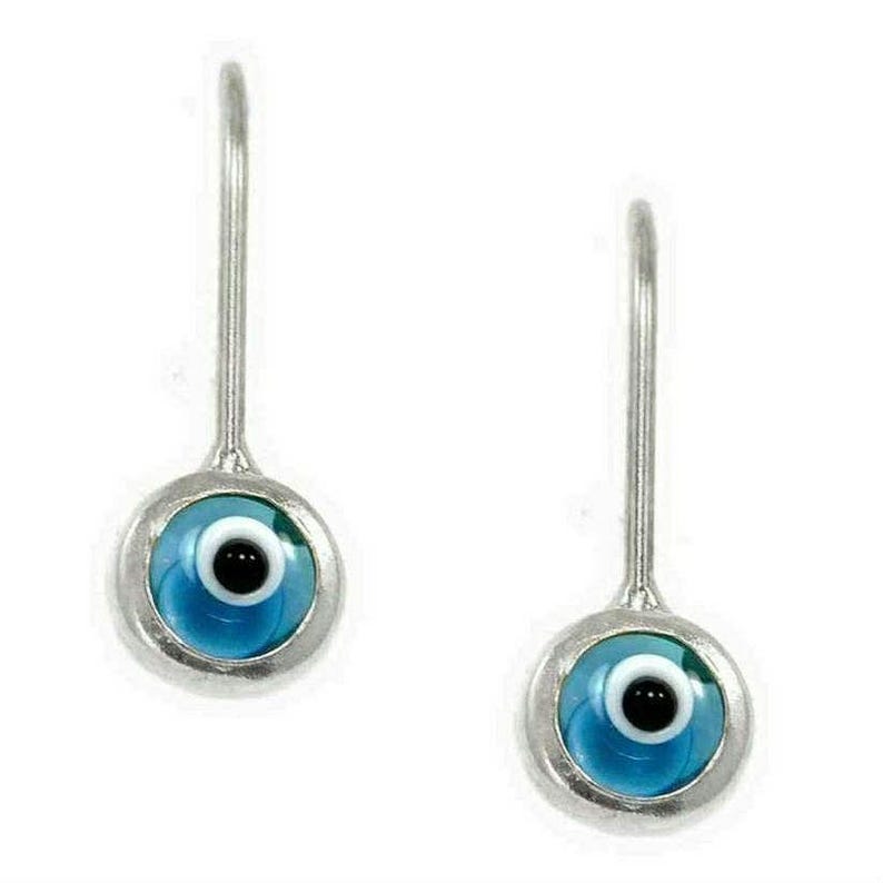 K&ouml;nnte beinhalten: Ein Paar silberne Ohrringe mit blauen b&ouml;sen Augen-Anh&auml;ngern. Die Anh&auml;nger sind rund und haben eine wei&szlig;e Pupille und eine schwarze Iris.