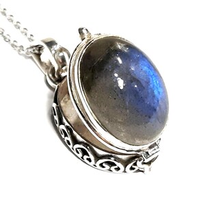 Peut inclure: Un collier avec un pendentif en argent en forme de m&eacute;daillon orn&eacute; d'une pierre de labradorite bleue et grise. Le m&eacute;daillon s'ouvre pour r&eacute;v&eacute;ler un petit espace &agrave; l'int&eacute;rieur.