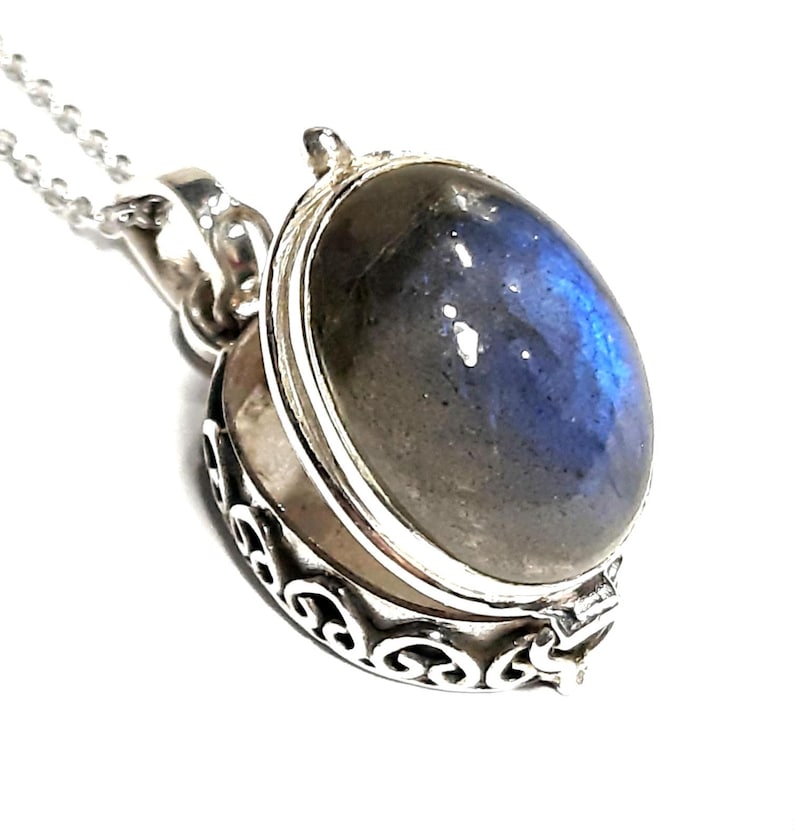 Peut inclure: Un collier avec un pendentif en argent en forme de m&eacute;daillon orn&eacute; d'une pierre de labradorite bleue et grise. Le m&eacute;daillon s'ouvre pour r&eacute;v&eacute;ler un petit espace &agrave; l'int&eacute;rieur.