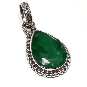 May include: A silver pendant with a teardrop-shaped green gemstone set in a beaded border.