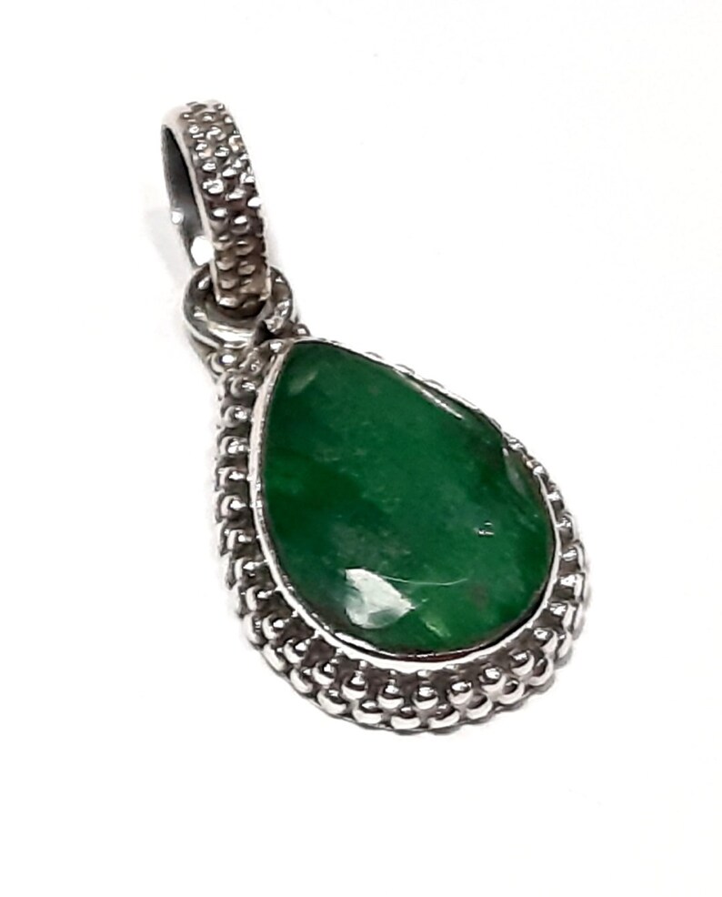 May include: A silver pendant with a teardrop-shaped green gemstone set in a beaded border.