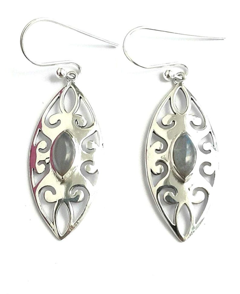 May include: A pair of silver earrings with a delicate filigree design and a gray gemstone in the center.