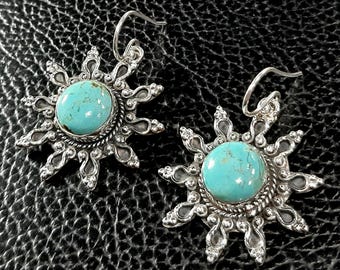 May include: A pair of silver earrings with turquoise stones set in a sunburst design.
