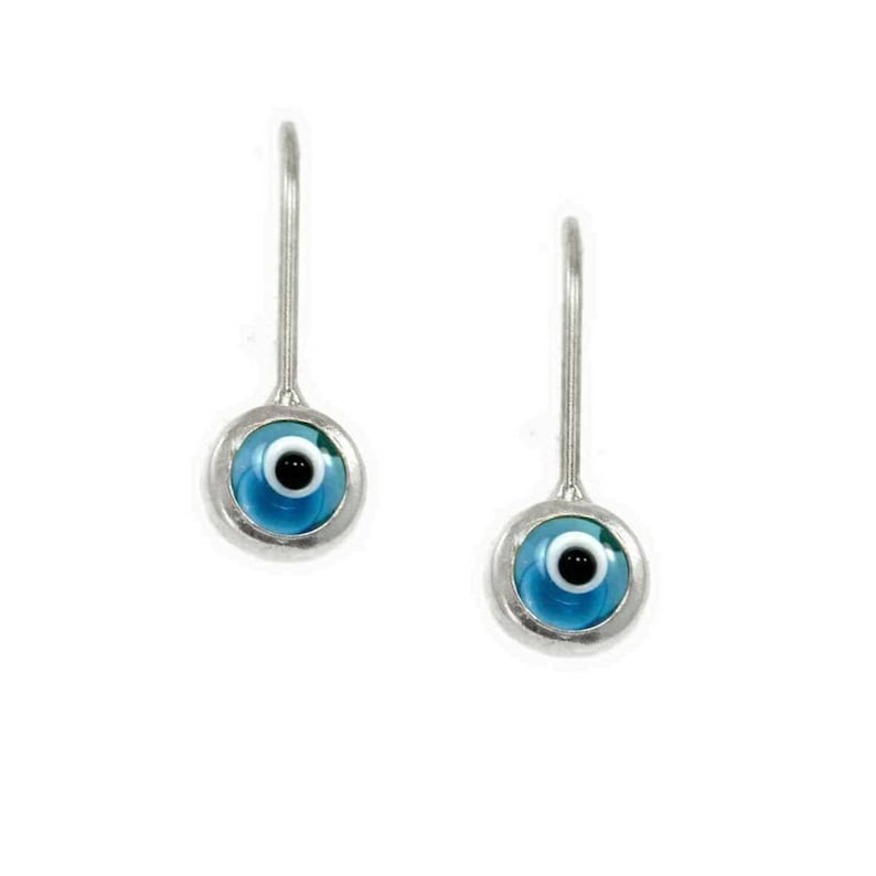 K&ouml;nnte beinhalten: Ein Paar silberne Ohrringe mit blauen b&ouml;sen Augen-Anh&auml;ngern. Die Anh&auml;nger sind rund und haben eine wei&szlig;e Mitte mit einer schwarzen Pupille.