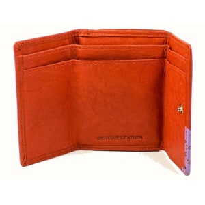 May include: An orange leather trifold wallet with a stitched design and the words "GENUINE LEATHER" printed on the inside.