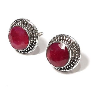Può includere: Un paio di orecchini d'argento con pietre preziose di rubino rosso incastonate in una cornice d'argento decorativa.