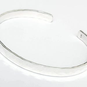 May include: A silver hammered bangle bracelet. The bracelet is smooth and has a polished finish.