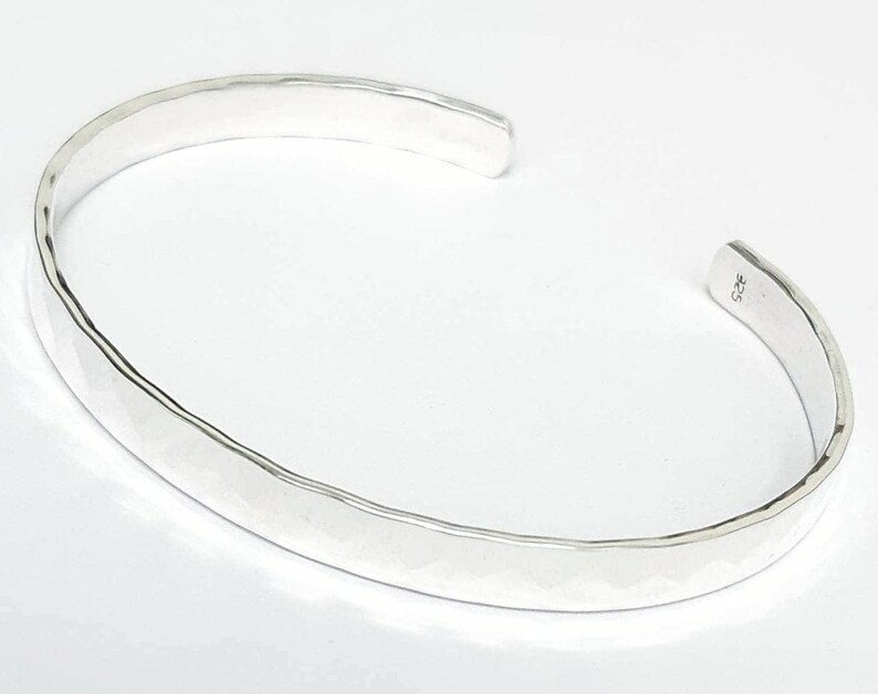 May include: A silver hammered bangle bracelet. The bracelet is smooth and has a polished finish.