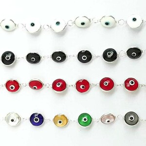May include: A set of silver bracelets with various colored evil eye charms. The charms are round and have a white, black, red, blue, green, gold, or pink eye in the center.
