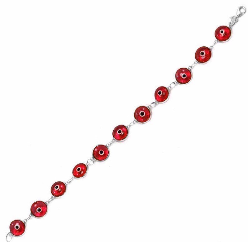May include: A silver bracelet with red evil eye charms. The bracelet is made of a chain with round red charms with a black eye in the center.