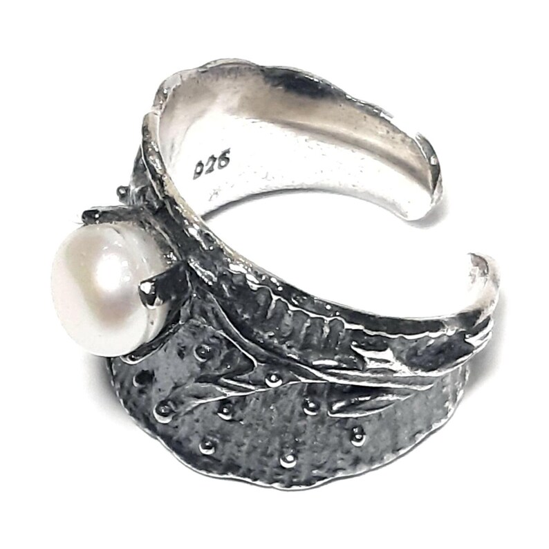 May include: A silver ring with a textured, leaf-like design and a white pearl. The ring is marked with the number "926".