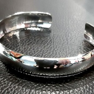May include: A silver bangle bracelet with a smooth, polished finish.