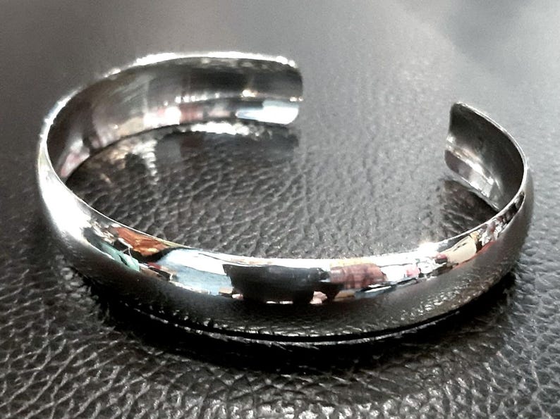 May include: A silver bangle bracelet with a smooth, polished finish.