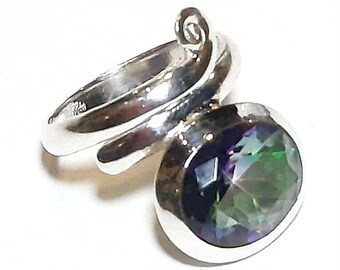 May include: A sterling silver ring with a swirling band design. The ring features a large, round, iridescent gemstone with shades of green, blue, and purple. The gemstone is set in a bezel setting, and the ring is displayed against a white background.