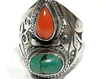 May include: A silver ring with an intricate design featuring a coral and turquoise stone. The ring has a detailed floral pattern and a twisted band.