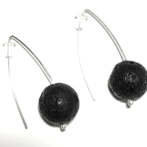 Puede incluir: Un par de pendientes de plata con cuentas de roca de lava negra. Los pendientes son de estilo colgante y tienen un diseño sencillo.