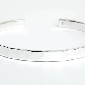 May include: A silver hammered bangle bracelet. The bracelet is smooth and shiny.