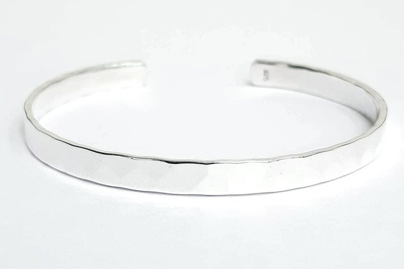 May include: A silver hammered bangle bracelet. The bracelet is smooth and shiny.