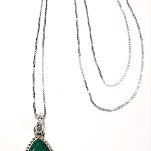 May include: A silver chain necklace with a teardrop-shaped pendant featuring a green gemstone.