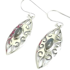 May include: Silver dangle earrings with a delicate filigree design and a gray gemstone in the center.