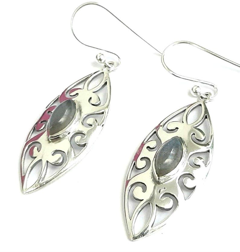 May include: Silver dangle earrings with a delicate filigree design and a gray gemstone in the center.