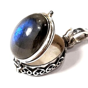 Peut inclure: Un collier avec un pendentif en argent en forme de m&eacute;daillon orn&eacute; d'une pierre de labradorite bleue. Le m&eacute;daillon est ouvert, r&eacute;v&eacute;lant un petit compartiment &agrave; l'int&eacute;rieur.