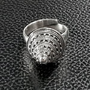 May include: A silver ring with a cone-shaped design. The cone is made up of multiple layers of intricate detailing, including small beads and lines.