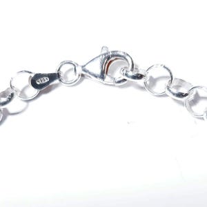 Puede incluir: Un brazalete de cadena de plata con cierre de mosquet&oacute;n. La cadena est&aacute; hecha de peque&ntilde;os eslabones redondos.