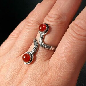 May include: A silver ring with a textured snake design and two red carnelian stones.