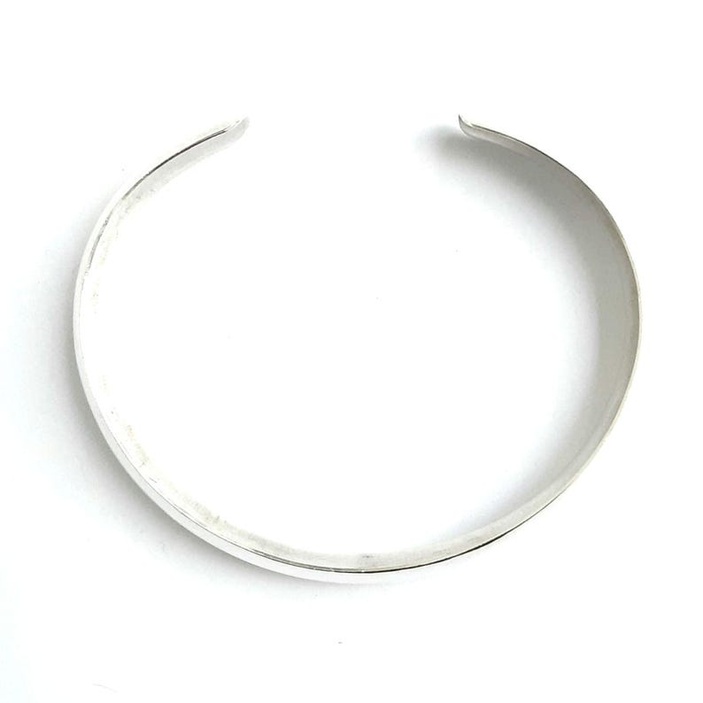 May include: A silver bangle bracelet with a smooth, polished finish.