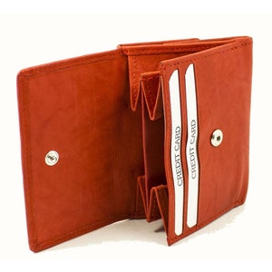 May include: A small, orange leather wallet with two card slots labeled "CREDIT CARD". The wallet is open and the inside is visible.