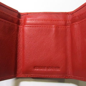 May include: Red leather trifold wallet with a snap closure and the words "Genuine Leather" embossed on the inside.
