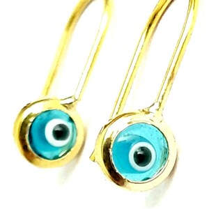 K&ouml;nnte beinhalten: Ein Paar goldene Ohrringe mit blauen b&ouml;sen Augen-Anh&auml;ngern. Die Ohrringe sind aus Gold und haben ein schlichtes Design. Die b&ouml;sen Augen-Anh&auml;nger sind blau mit einem wei&szlig;en Kreis in der Mitte und einer schwarzen Pupille.