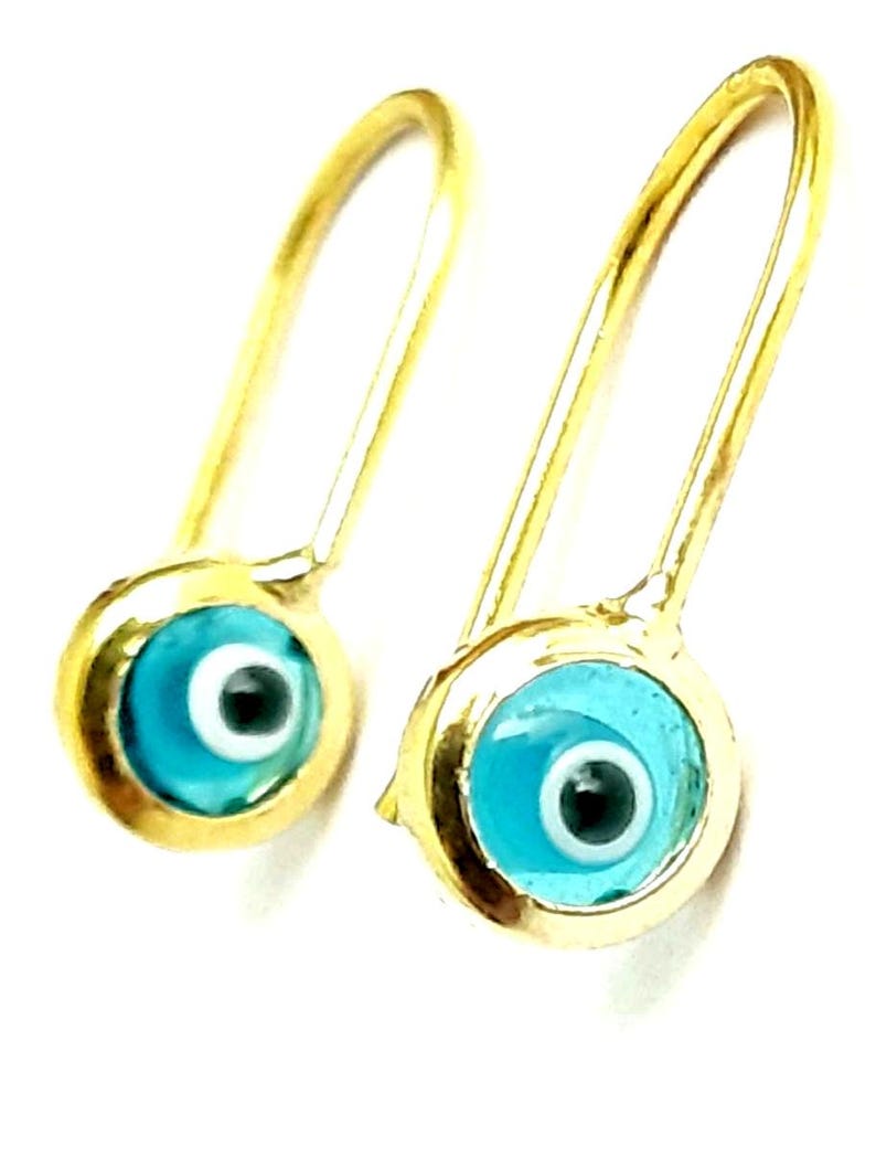 K&ouml;nnte beinhalten: Ein Paar goldene Ohrringe mit blauen b&ouml;sen Augen-Anh&auml;ngern. Die Ohrringe sind aus Gold und haben ein schlichtes Design. Die b&ouml;sen Augen-Anh&auml;nger sind blau mit einem wei&szlig;en Kreis in der Mitte und einer schwarzen Pupille.